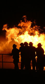 Firemen in front of a large blazing fire